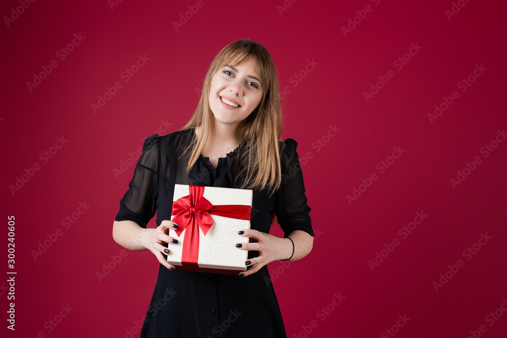 woman holding gift box with red ribbon wearing dress isolated over red woman holding gift box with red ribbon wearing dress isolated over red
