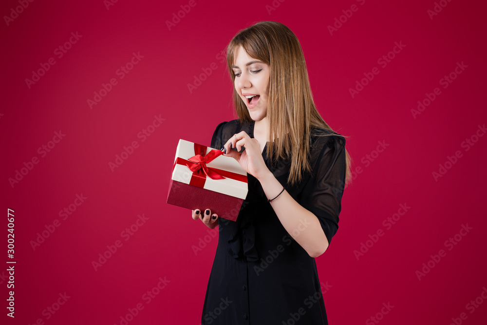 Fototapeta premium woman holding gift box with red ribbon wearing dress isolated over red