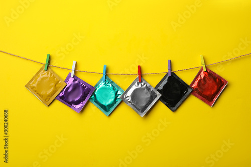 Принти на полотні Colorful condoms hanging on clothesline against yellow background