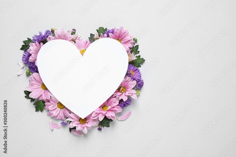 Beautiful chamomile flowers and heart shaped paper card on white background, top view with space for text