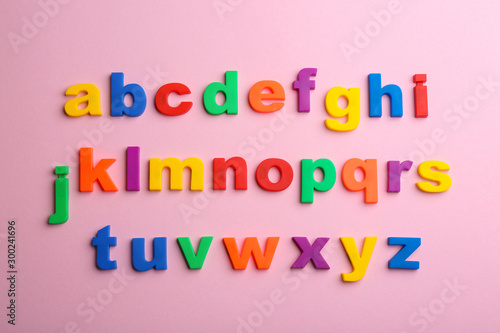 Plastic magnetic letters on pink background  flat lay. Alphabetical order