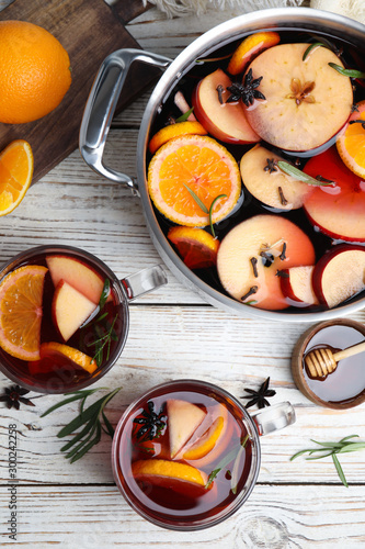 Tasty mulled wine with spices on white wooden table, flat lay