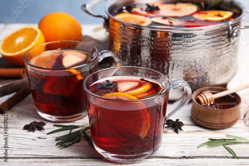 Tasty mulled wine with spices on white wooden table