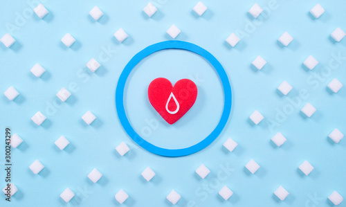 Symbol of diabestes with sugar cube and red heart on pastel blue background. World diabestes day concept.