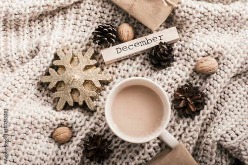 Winter composition. Coffee cup, candle, nuts and on sweater background.