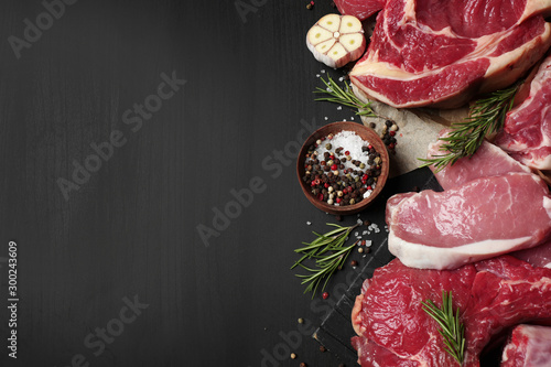 Flat lay composition with fresh meat on dark table. Space for text photo