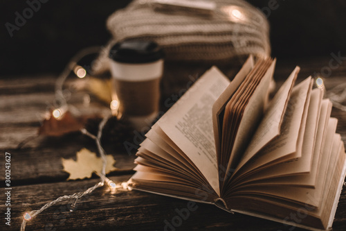 Autumn composition. Cup with coffee, garland, book, cones on a wooden background.