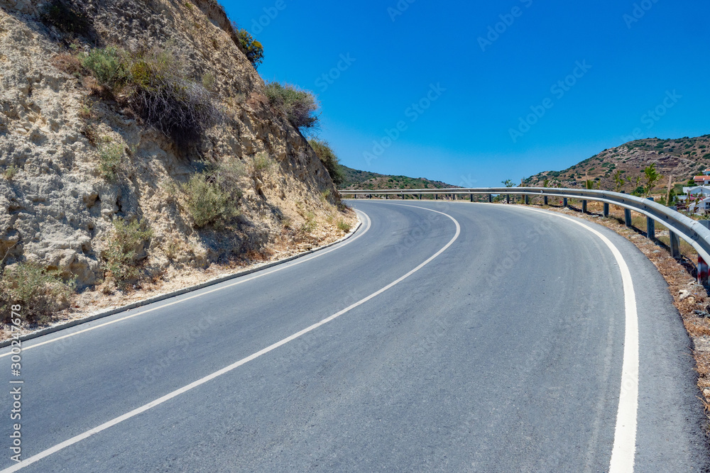 Mountain road. Highway through the mountains. Highway for cars in the highlands. Mountain road on the background of blue sky. Concept - road construction in difficult conditions. Cyprus.
