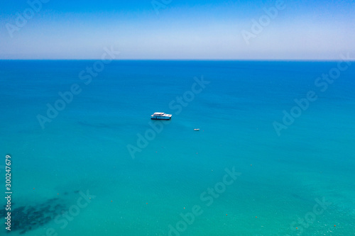 Yacht. Ocean top view. A small yacht is sailing across the ocean. The concept is water travel. Traveling by ship. Yacht aerial view. A small ship is sailing on the sea. Concept - yachts for rent. © Grispb
