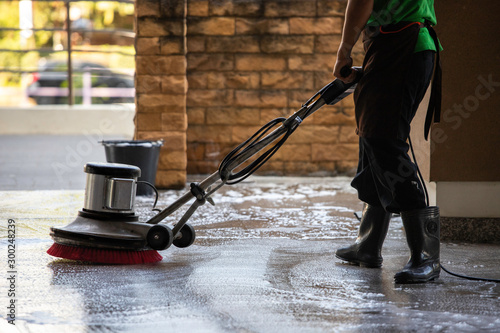 A man worker cleaning the floor with polishing machine