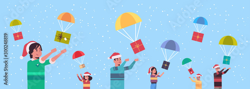 people catching gift present boxes falling down with parachutes merry christmas happy new year holiday celebration concept men women wearing santa hats horizontal portrait vector illustration