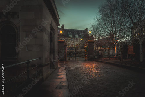GLASGOW, SCOTLAND, DECEMBER 16, 2018: Creepy cobbled street surrounded by old European style buildings. Illuminated only with weak light from street lamps. © Andres Conema