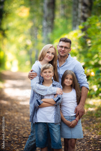 Portrait of happy family of four in a green summer park