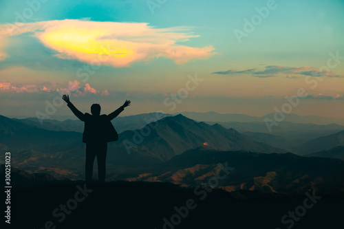 silhouette of man on mountain top over sky and sun light background,business, success, leadership, achievement and people concept