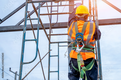 Fototapeta Construction worker wearing safety harness belt during working at high place