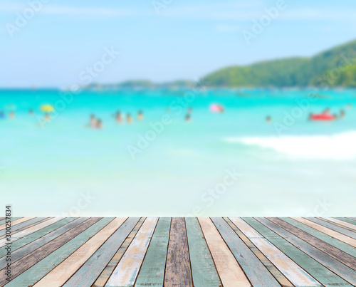 Wood table top with blurred people at the beach