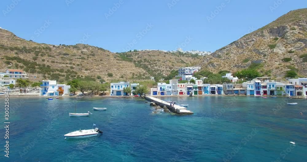 WA Aerial shot of deep blue water in front of a beautiful fishing village on Mylos in the Aegean Sea in Greece. WA Aerial shot of deep blue water in front of a beautiful fishing village on Mylos in the Aegean Sea in Greece.