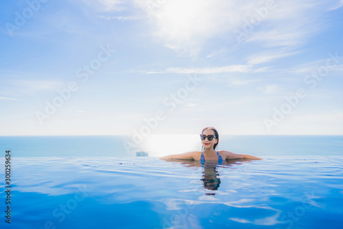 Portrait beautiful young asian woman smile happy relax around swimming pool in hotel resort with sea and ocean view