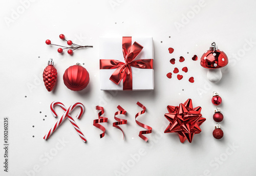 Christmas decoration, gift boxes with red ribbon, sparkles, confetti, christmas candy and balls on white background. Xmas and Happy New Year holiday. Flat lay, top view