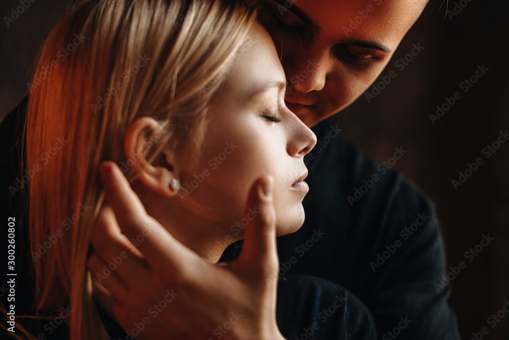 Side view portrait of a beautiful young woman sitting with closed eyes while her boyfriend is touching her face. Side view portrait of a beautiful young woman sitting with closed eyes while her boyfriend is touching her face.