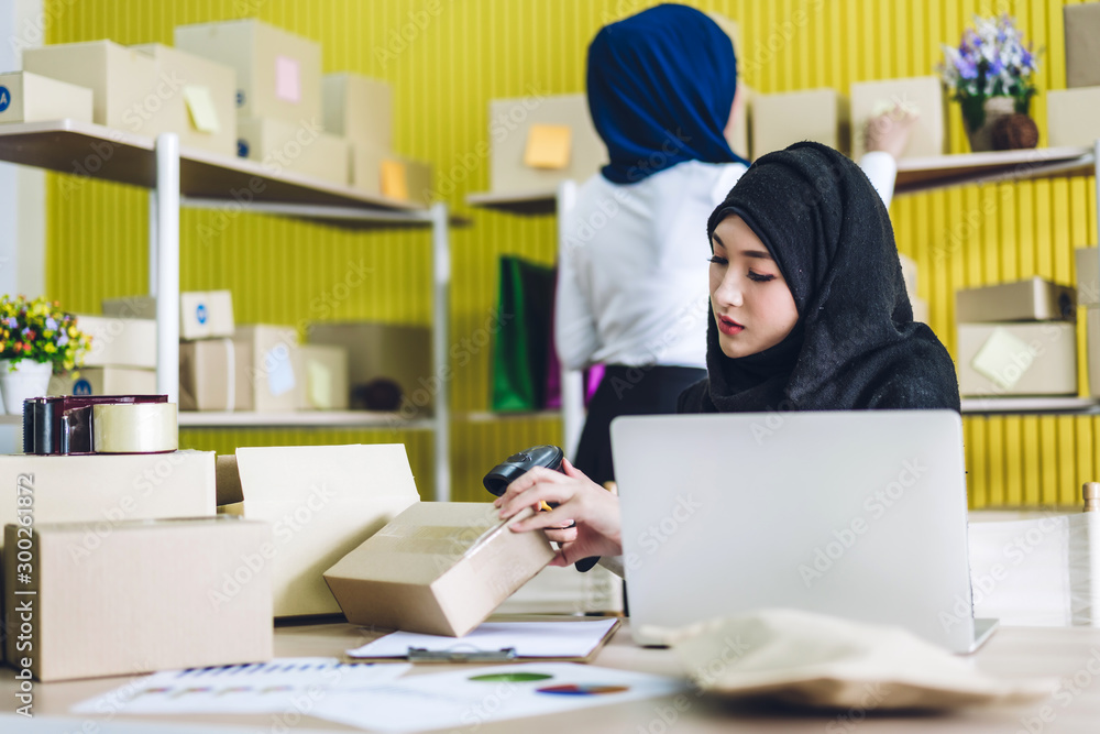 Muslim asian woman freelancer sme business online shopping working and checklist order with cardboard box on table at home - Business online shipping and delivery concept Muslim asian woman freelancer sme business online shopping working and checklist order with cardboard box on table at home - Business online shipping and delivery concept