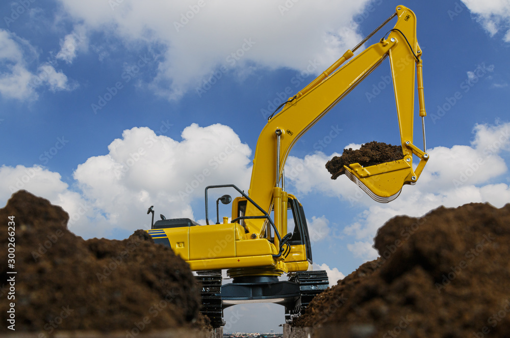 Excavators are digging the soil in the construction site on the blue sky background Excavators are digging the soil in the construction site on the blue sky background