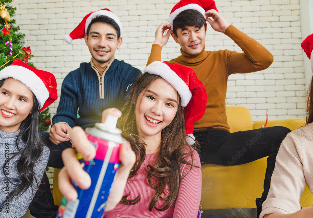 Fototapeta premium Group of young smile people in winter season playing and feel funny from color string spray for celebrate in Christmas party