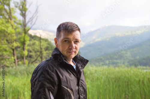 Handsome man unshaven face and stylish hair on natural landscape