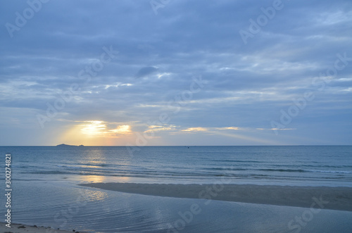 A picturesque tropical yellow coloured cloudy coastal sunrise seascape in a steel blue sky. Thailand.