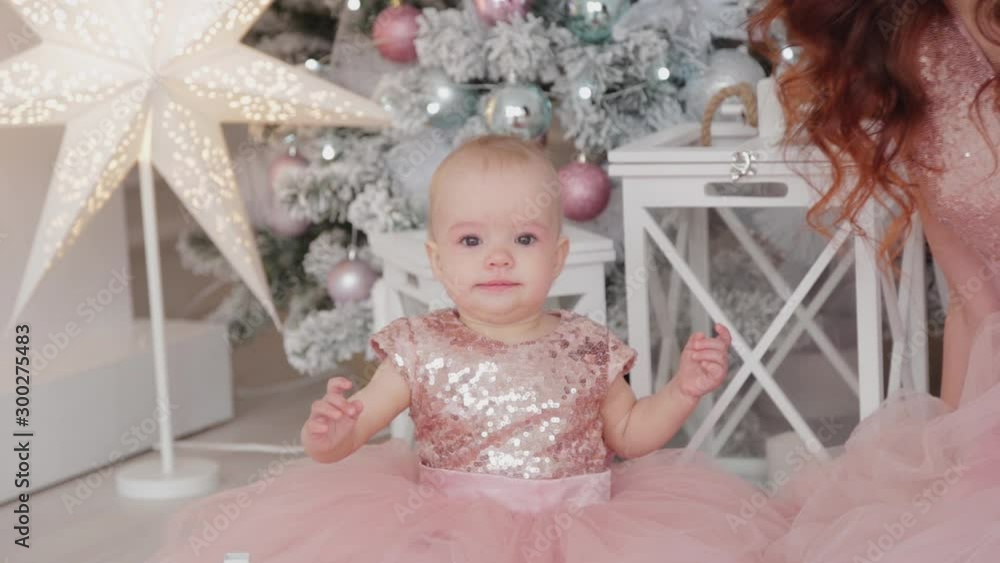 Beautiful mother with a one-year-old daughter in beautiful dresses and New Year's decor. New Year 2020.