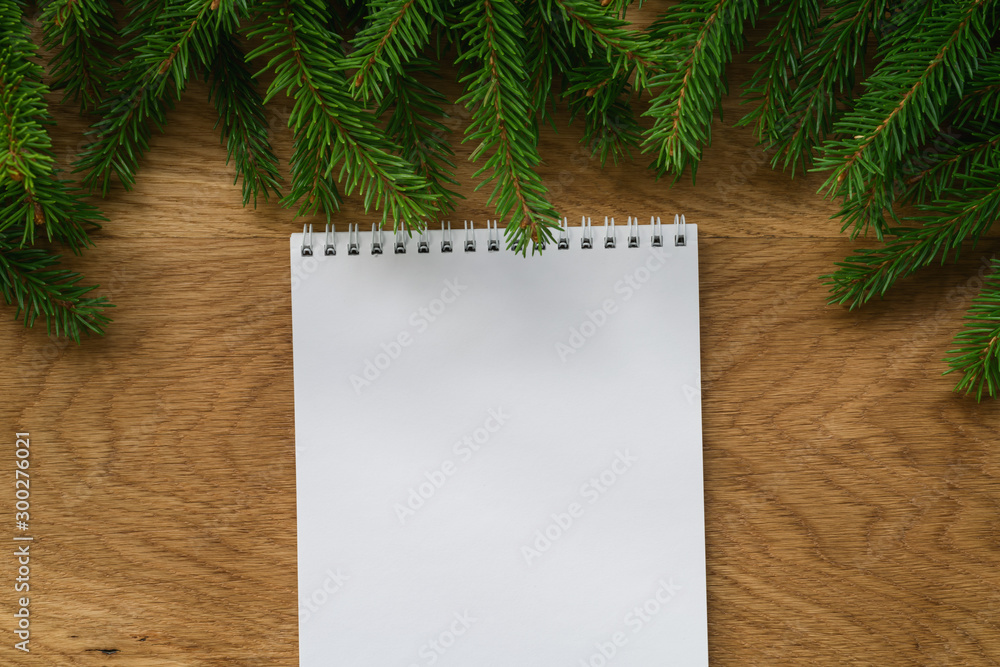 Flat lay empty notepad with spruce twigs on oak wood surface Flat lay empty notepad with spruce twigs on oak wood surface