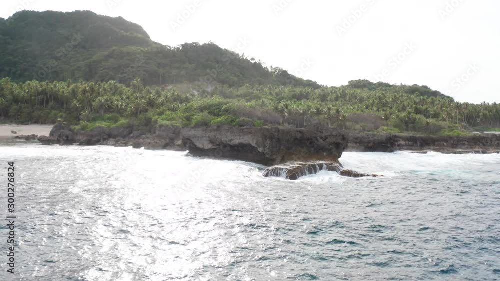 Aerial dolly of waves from sea crashing onto cliff of beautiful tropical island Aerial dolly of waves from sea crashing onto cliff of beautiful tropical island