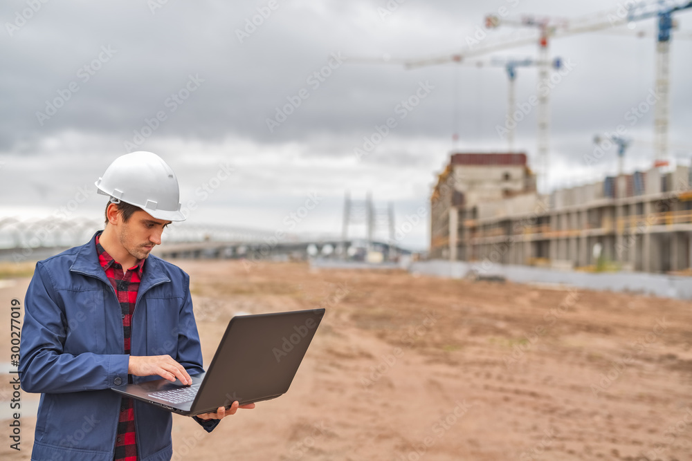 civil engineer in a white helmet looking documents on the background of construction civil engineer in a white helmet looking documents on the background of construction