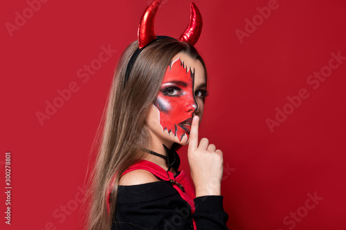 Devil. Funny imp with red horns and black bow tie at Halloween party. Halloween makeup. The devil costume.