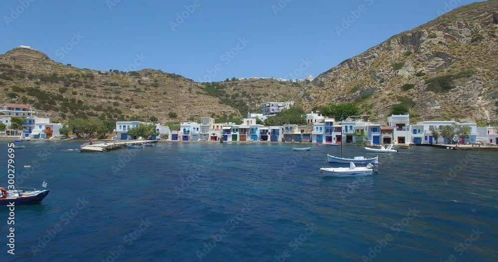 AERIAL of Mandrakia Fishing Village on the island of Milos Cycladic in the Aegean Sea Mediterranean of Greece. Wide angle summertime daytime exterior approach establishing shot. AERIAL of Mandrakia Fishing Village on the island of Milos Cycladic in the Aegean Sea Mediterranean of Greece. Wide angle summertime daytime exterior approach establishing shot.