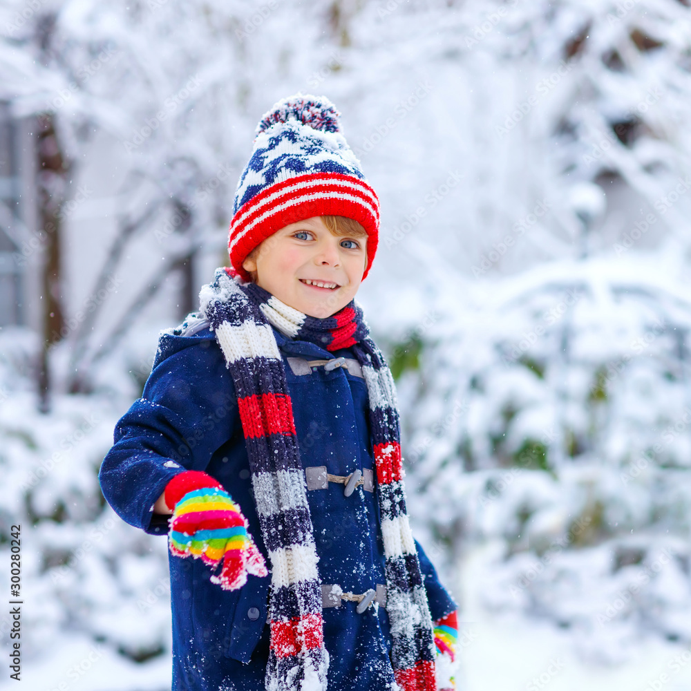 Preschool kid boy in colorful clothes playing outdoors during strong  snowfall. Active leisure with children in winter on cold snowy days. Happy  child having fun, playing with snow. Winter fashion. Photos