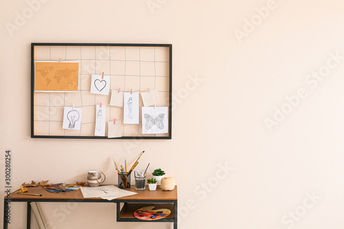 Comfortable workplace with mood board near light wall