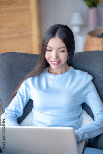 Freelance writer wearing blue sweater working on laptop photo