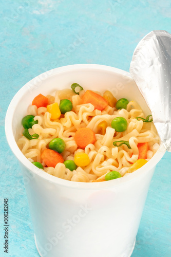 Ramen cup close-up, instant noodles in a plastic cup on a blue background photo