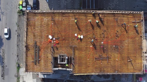 Electricians workers installing electric wires on rooftop of building under construction. Aerial view.