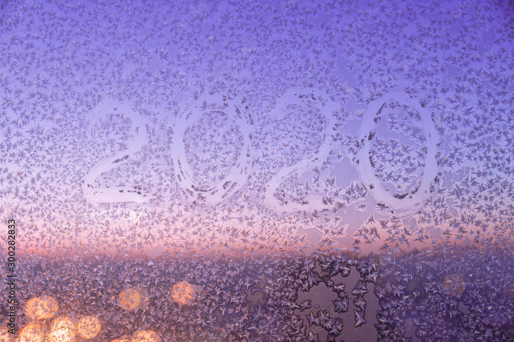 Abstract multicolored texture of frosty pattern on glass with the number 2020