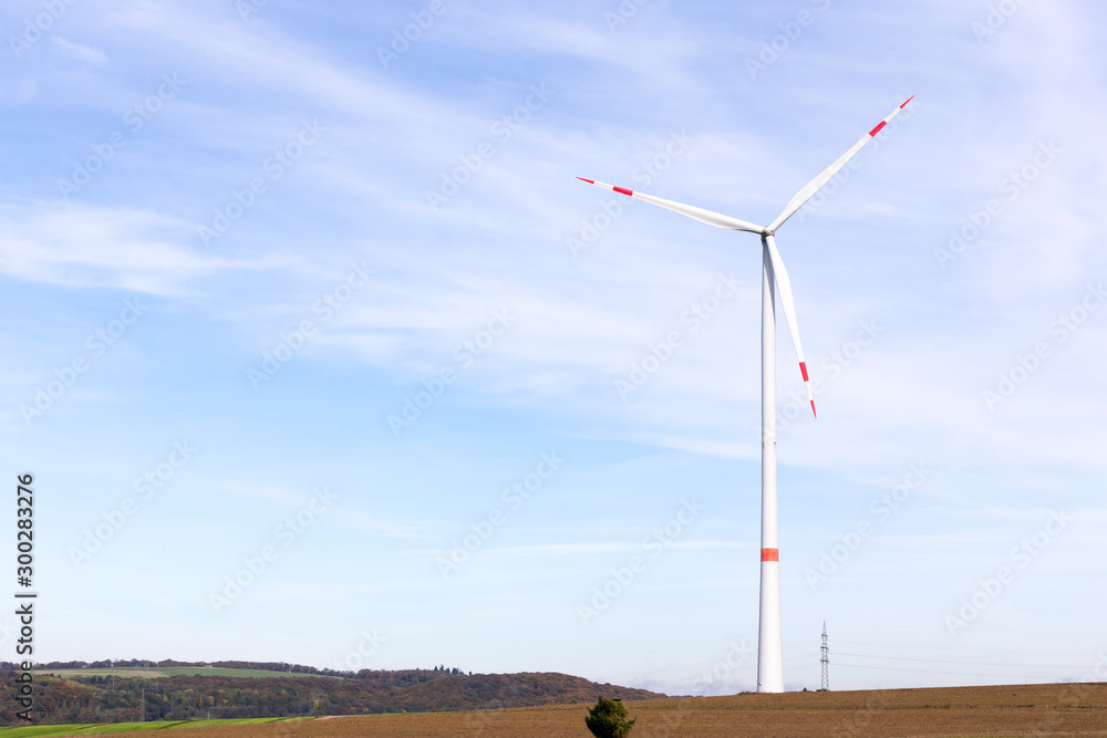 Fototapeta premium A windmill on a field with blue sky