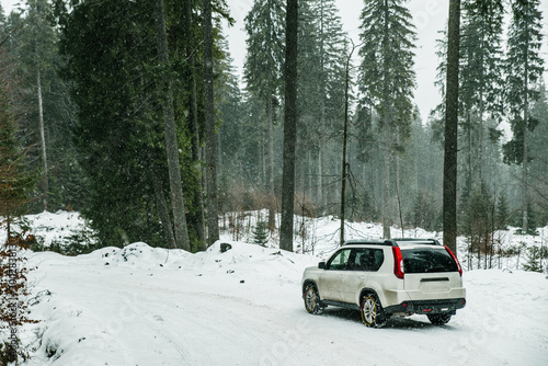 suv car with chain on wheels in snowed forest