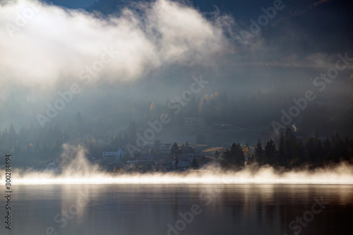 Lovely autumnal landscape with fog over the lake.