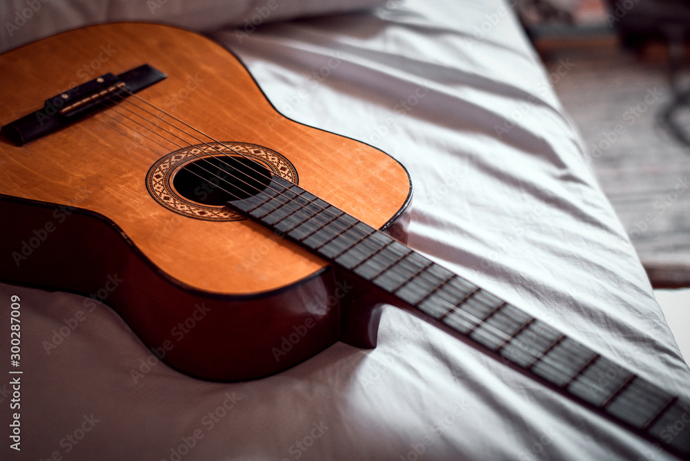 Obraz premium Old wooden acoustic guitar on the bed