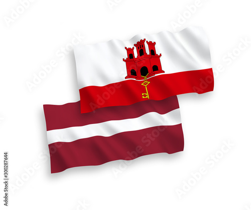 National vector fabric wave flags of Latvia and Gibraltar isolated on white background. 1 to 2 proportion.