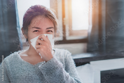 Sick asian woman sneezing on nose with tissue paper because air pollution prevent germs and viruses in symptoms, PM 2.5, selective focus. photo