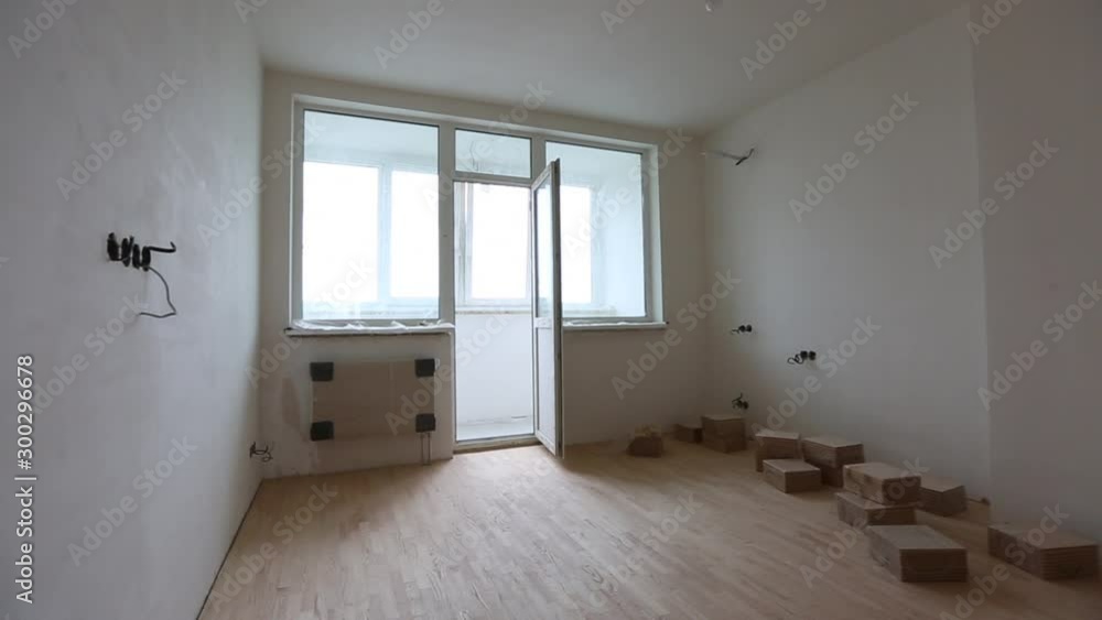 Vacant unfurnished room interior with wooden herringbone parquet floor and white walls and ceiling lit by down lights Vacant unfurnished room interior with wooden herringbone parquet floor and white walls and ceiling lit by down lights