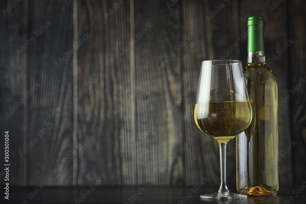 Transparent bottle of white dry wine on the table. White wine glass on a wooden background. - obrazy, fototapety, plakaty 