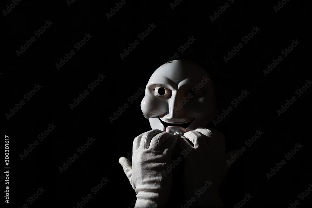 White scary mask on a black background with whites hand. White scary mask on a black background with whites hand.